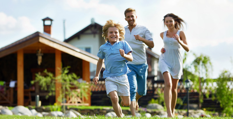 Familie läuft auf der Wiese vor einem Haus